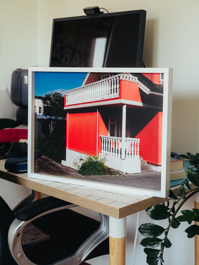 Fotografie Reykjavik 2022: stampa contemporanea con una casa dal colore rosso, incorniciata su un tavolo moderno.